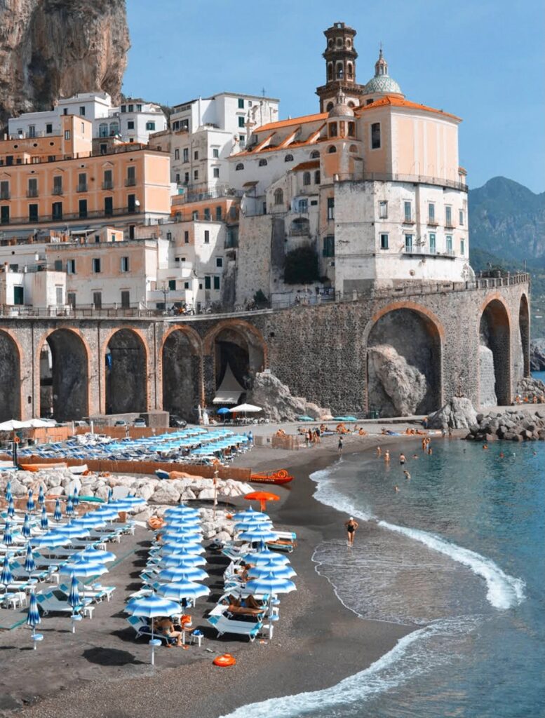 A view of the Atrani Beach Coastline with Atrani beach club and beach umbrellas on the Amalfi Coast, Italy.