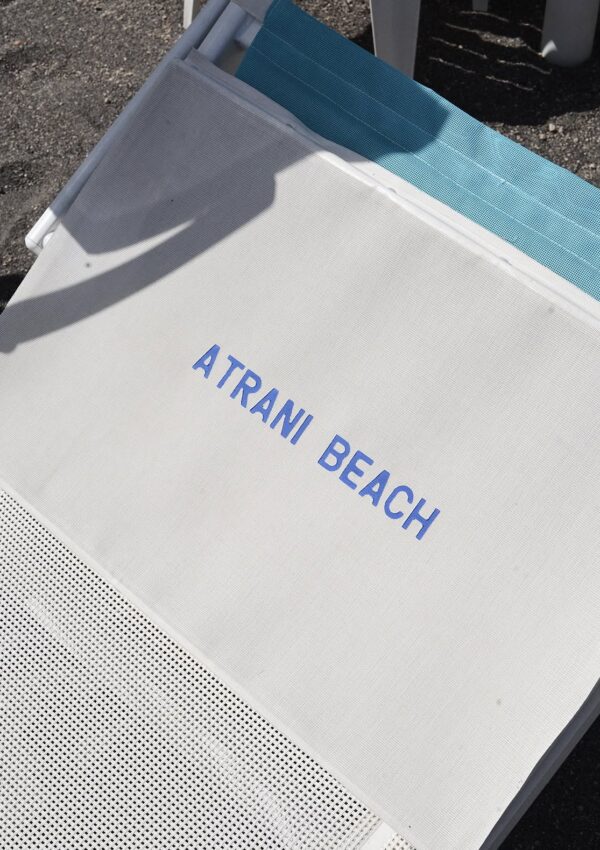 A beach lounger on the black sand beach at Atrani, Italy, Amalfi Coast.