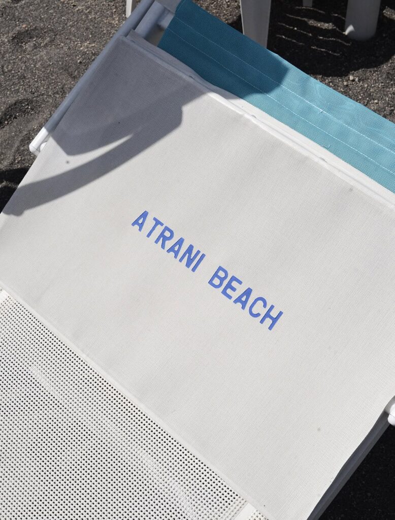 A beach lounger on the black sand beach at Atrani, Italy, Amalfi Coast.