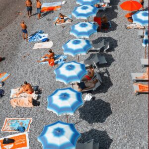 An aerial drone view of beach umbrellas at Atrani beach club in the Amalfi Coast.