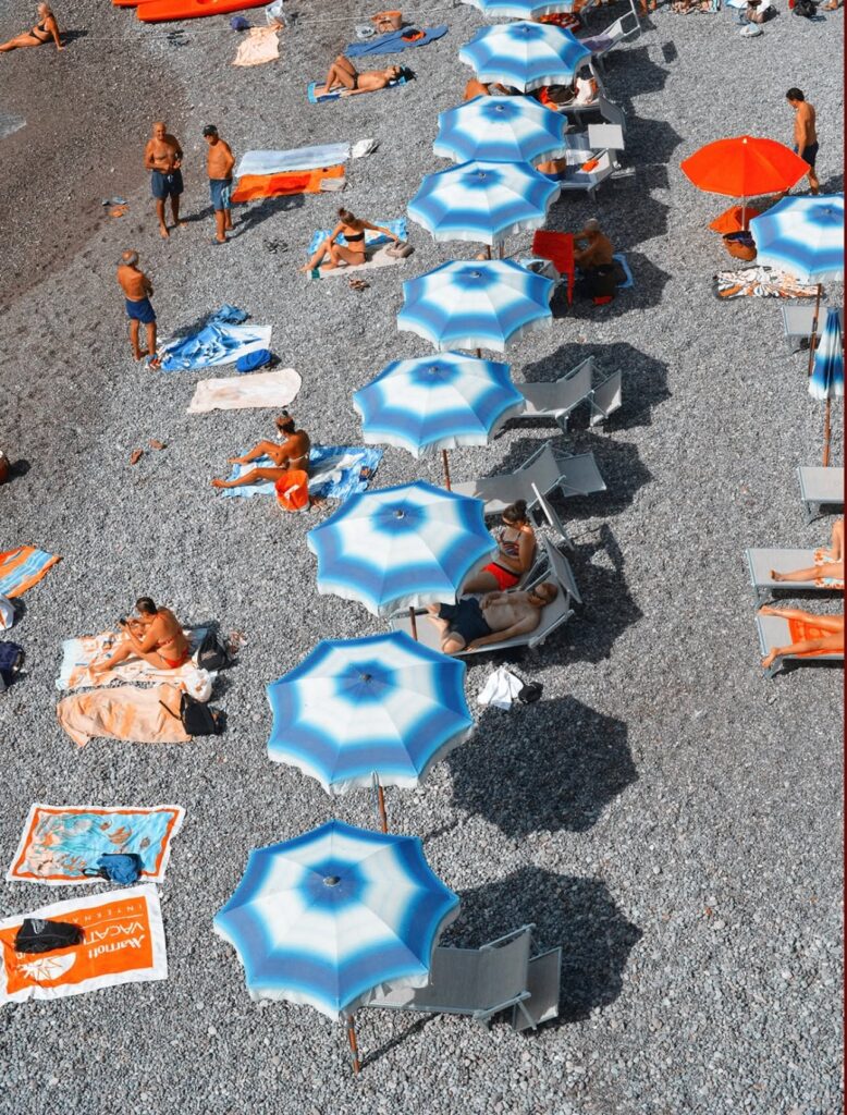 An aerial drone view of beach umbrellas at Atrani beach club in the Amalfi Coast.