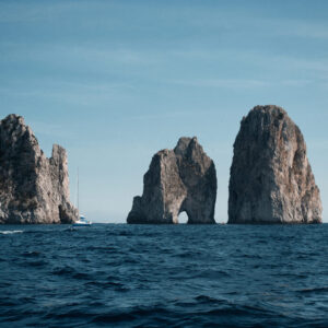 A view from the sea of the Faraglioni di Capri in the distance.