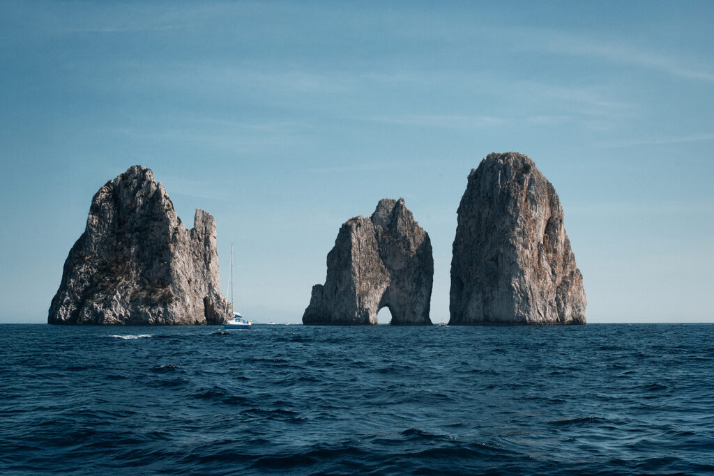 A view from the sea of the Faraglioni di Capri in the distance.