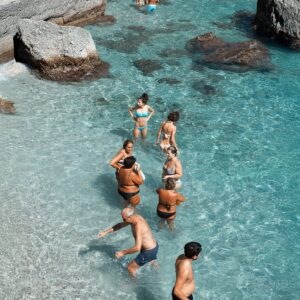 locals and tourists playing in the crystal clear waters at Marina Piccola beach in Capri, Italy.