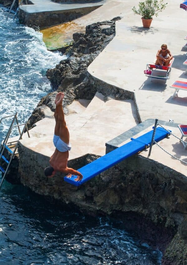 A swimmer diving from the rocks at Lido Capo di Conca on the Amalfi Coast, Italy