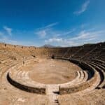 A large amphitheater with stone seating at the ancient ruins of Pompeii.