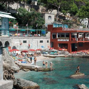 A photo of a restaurant near Marina Piccola beach in Capri Italy with sun beds and tourist relaxing at a Capri Beach Club.