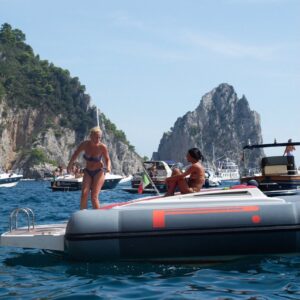 friends relaxing and jumping off of a boat into the water near Capri, Italy.