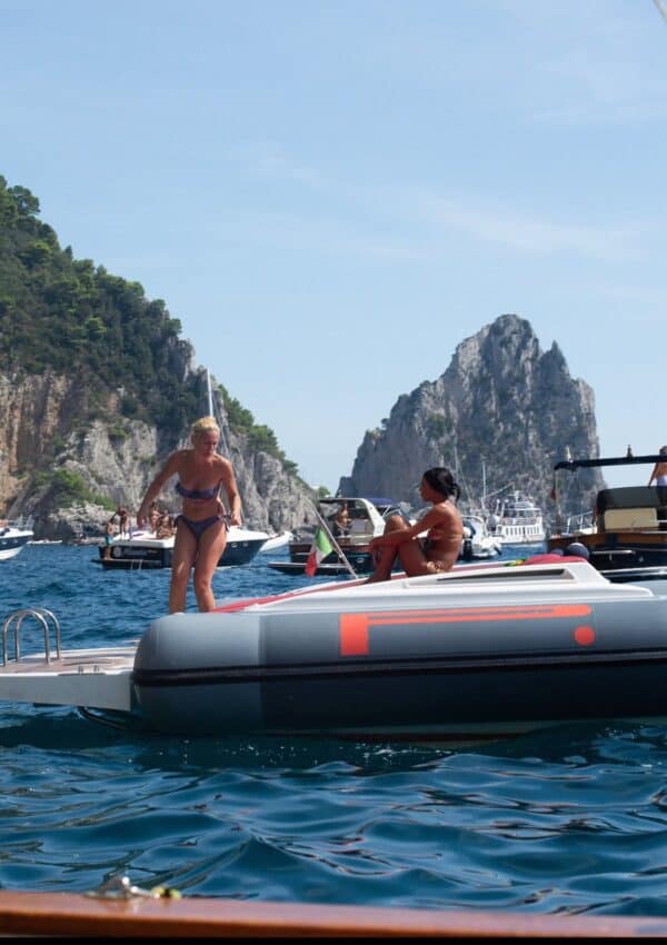 friends relaxing and jumping off of a boat into the water near Capri, Italy.