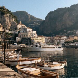 Wooden boats and a yacht below an Amalfi Coast town with cliffs