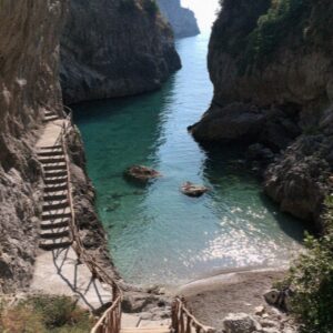 The hidden cove of Duoglio near Amalfi with turquoise water, cliffs and a wooden stair down to the beach