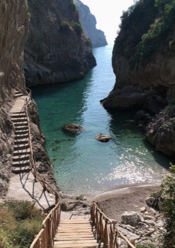 The hidden cove of Duoglio near Amalfi with turquoise water, cliffs and a wooden stair down to the beach