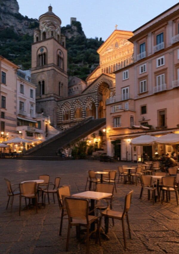 Cafe tables in an Amalfi piazza lit up in the evening