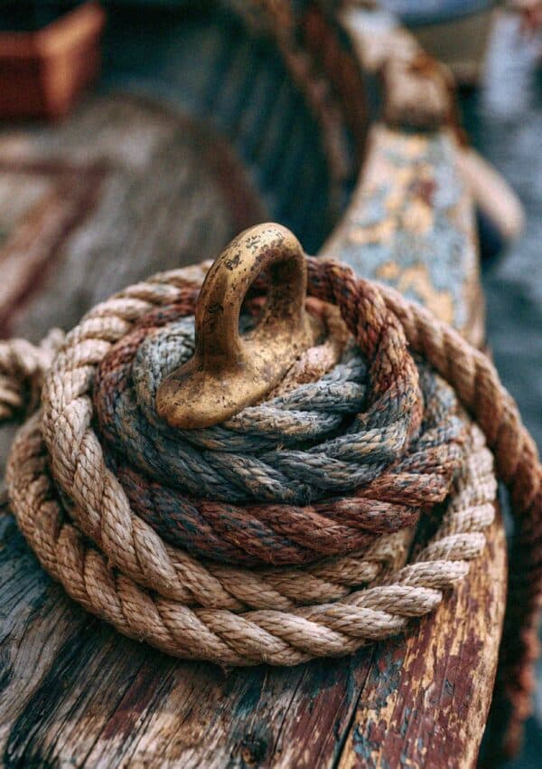 Coiled rope and a brass cleat on an old wooden fishing boat in Cinque Terre