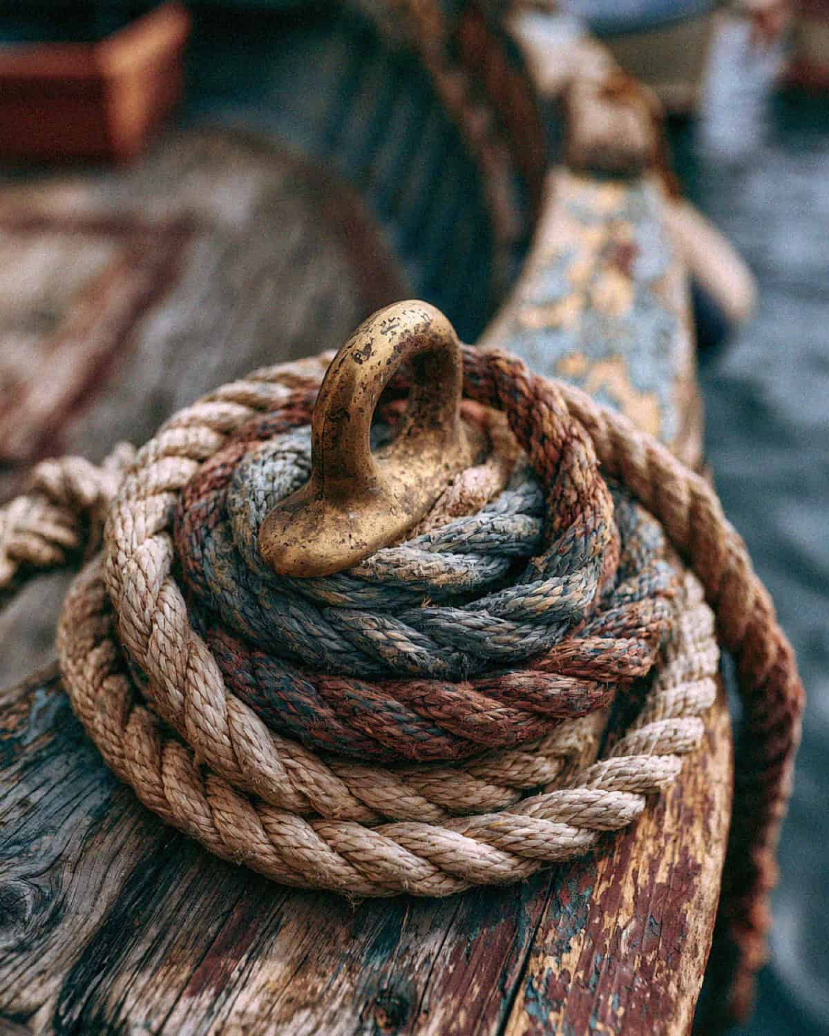 Coiled rope and a brass cleat on an old wooden fishing boat in Cinque Terre