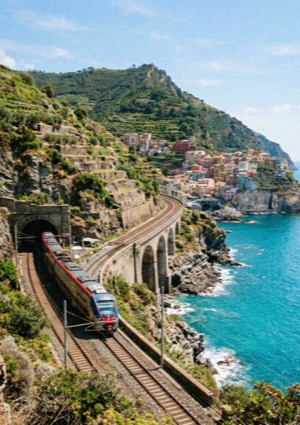 The Cinque Terre Express regional train on a coastal viaduct beside the turquoise sea