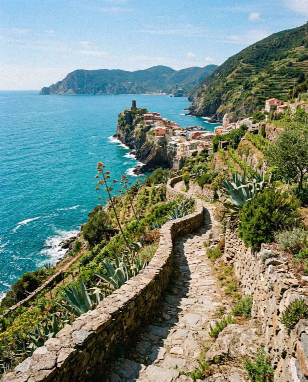 The rugged Cinque Terre coastline in Liguria Italy with a pastel village above the turquoise sea and terraced vineyards