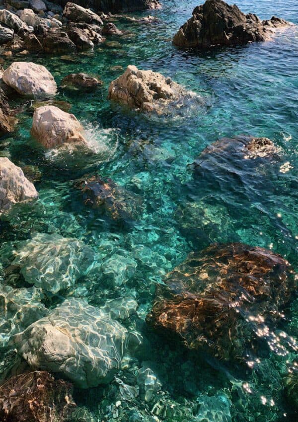 Crystal clear turquoise water over rocks in a cove on the Cinque Terre coast