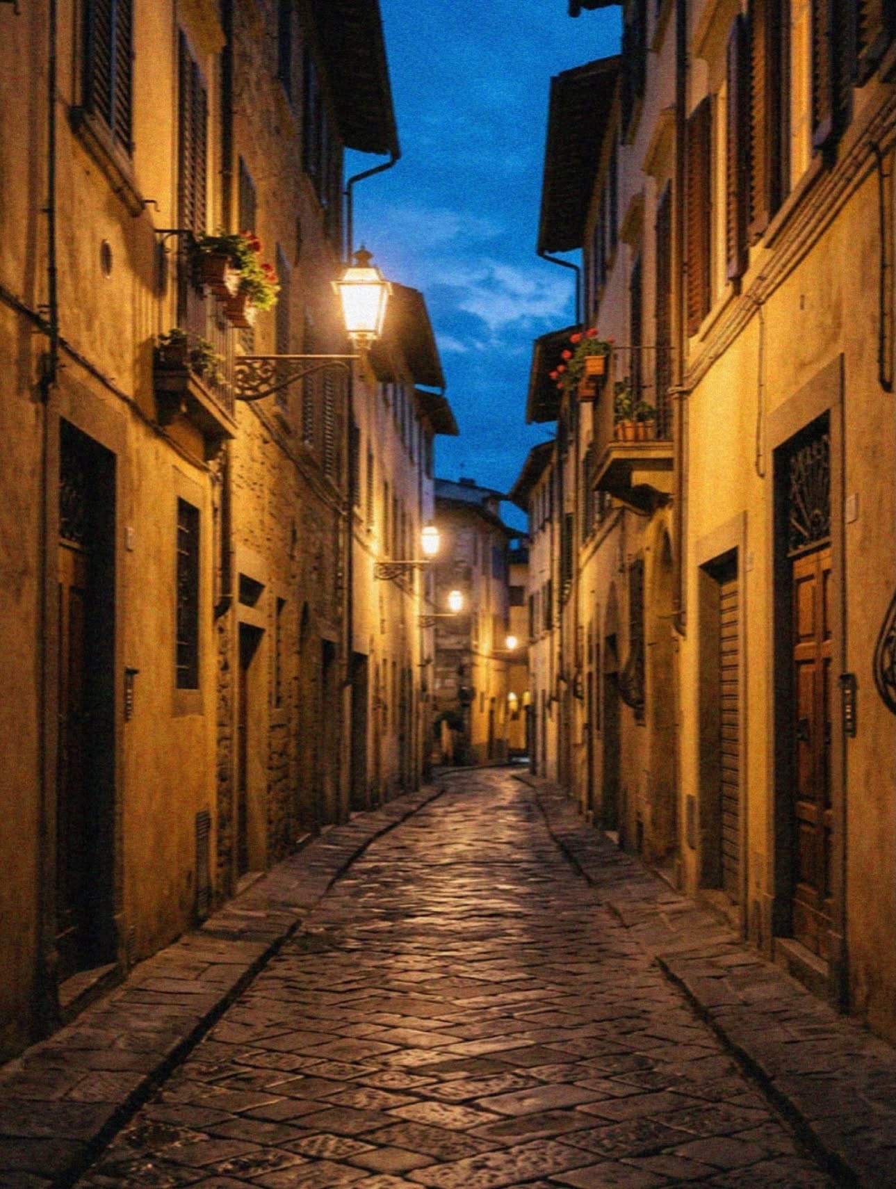A lamplit cobblestone lane in Florence at blue hour