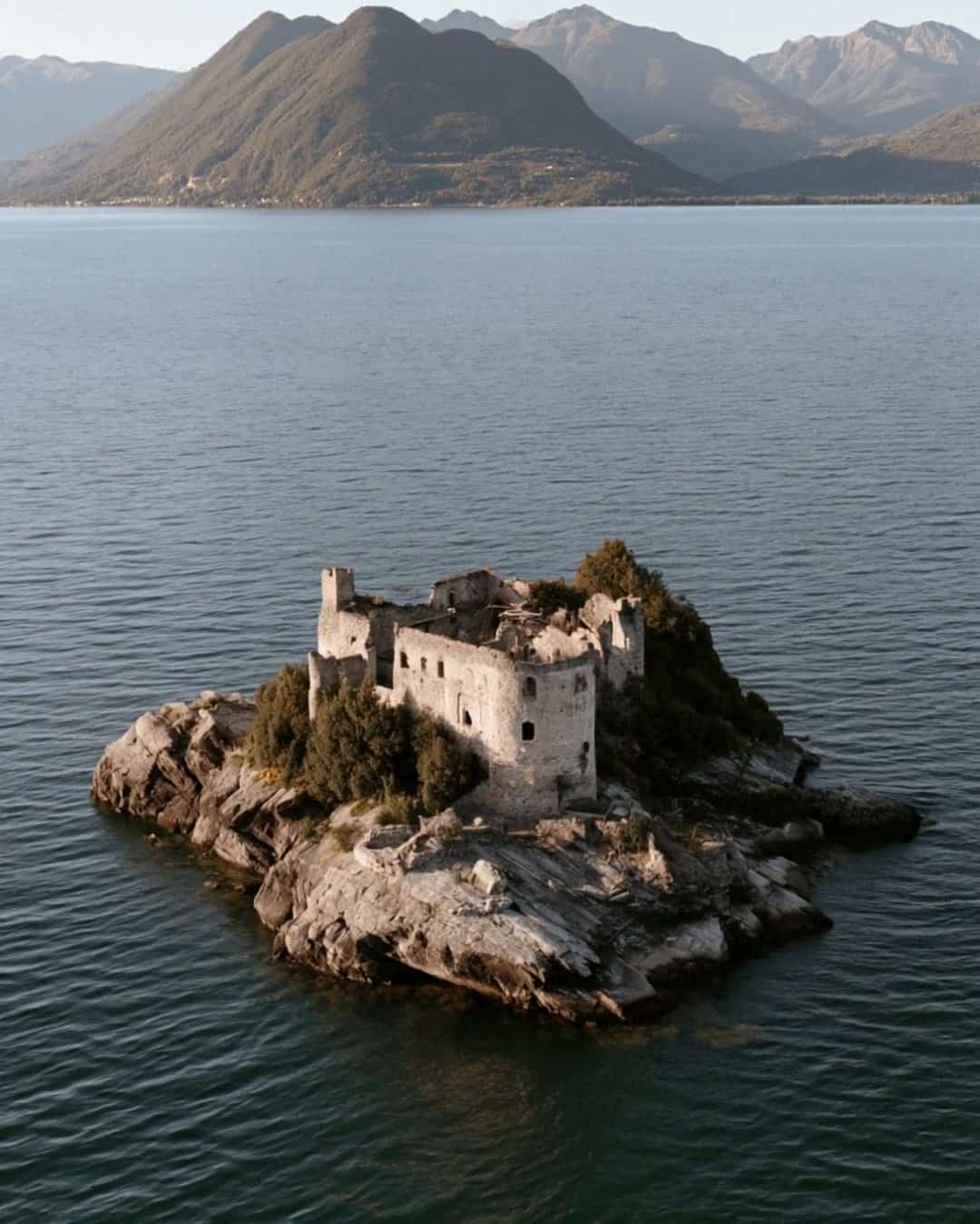 The ruined Cannero castle on its islet on Lake Maggiore with the mountains behind
