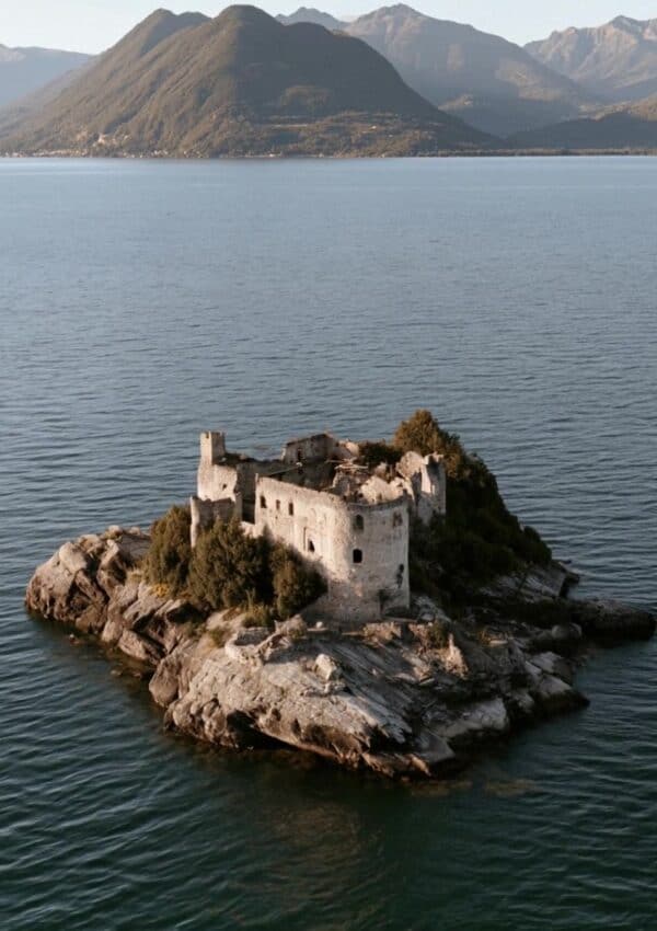 A ruined castle on a rocky islet on Lake Maggiore with the mountains behind