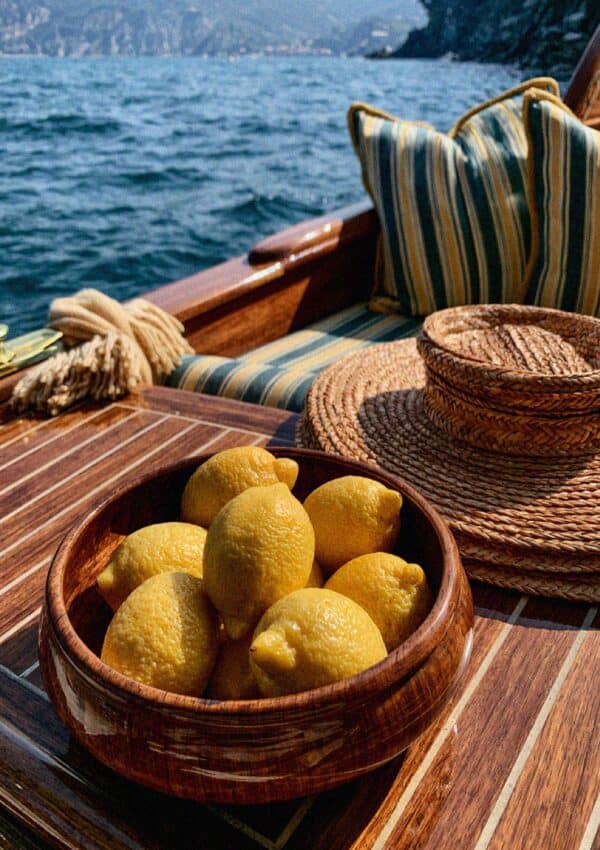 A wooden bowl of lemons on the deck of a classic wooden boat at sea in Cinque Terre