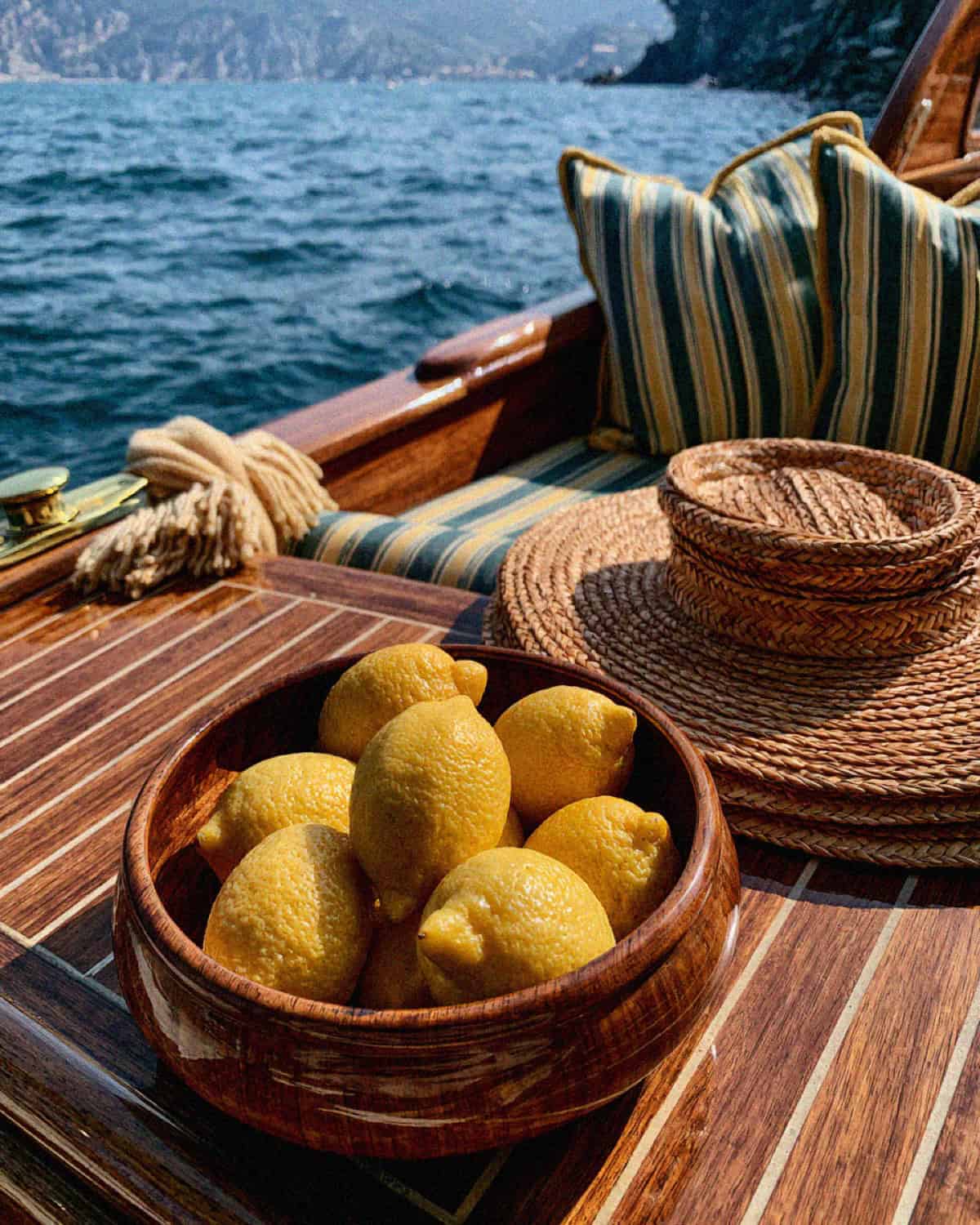A wooden bowl of lemons on the deck of a classic wooden boat at sea in Cinque Terre