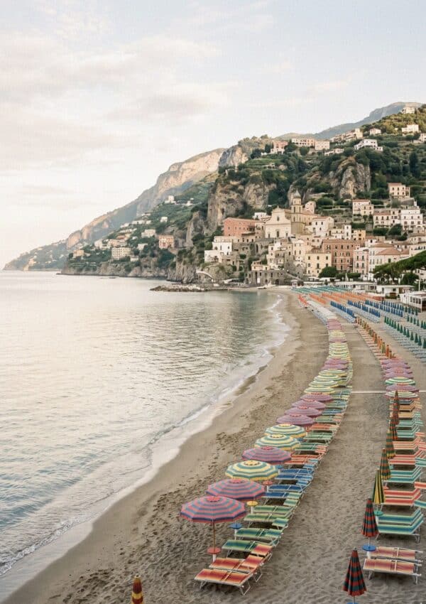 Rows of colorful striped umbrellas and empty sunbeds on Maiori's long sandy beach at early morning