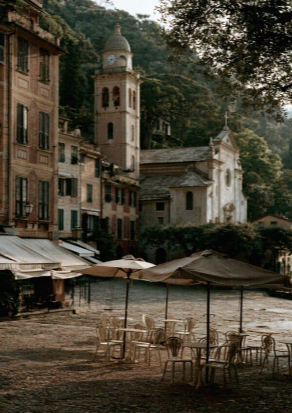 The Portofino church bell tower above the harbour with empty cafe tables
