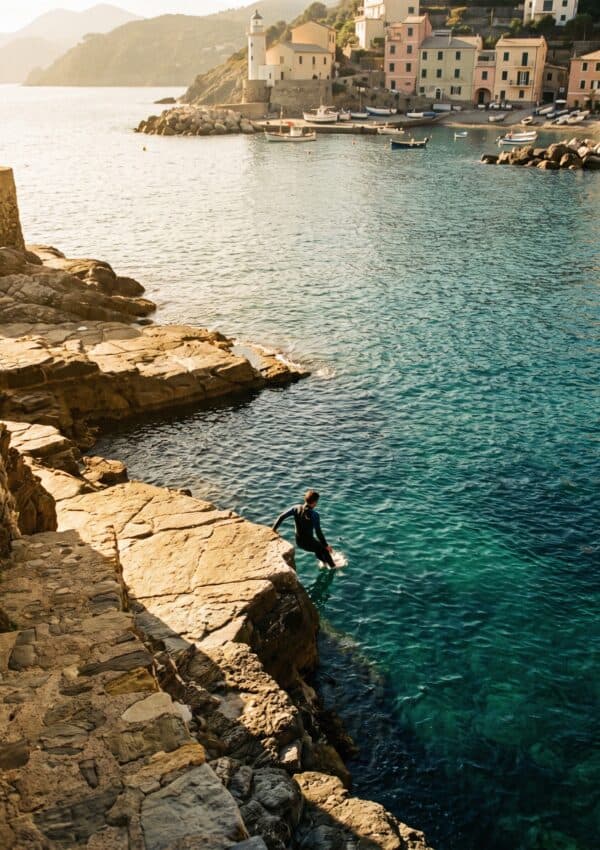 A swimmer entering the clear turquoise water off the rock ledges below the Portofino coast