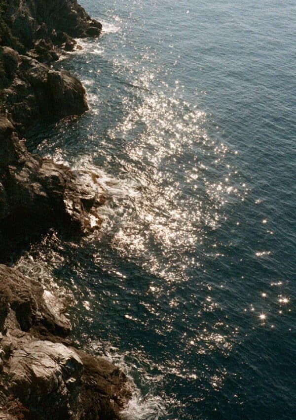 Sunlight sparkling on the deep blue sea off a rocky headland near Portofino