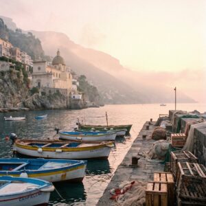 Small fishing boats moored in a harbor at dawn below a hillside town on the Amalfi Coast