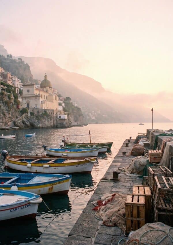 Small fishing boats moored in a harbor at dawn below a hillside town on the Amalfi Coast