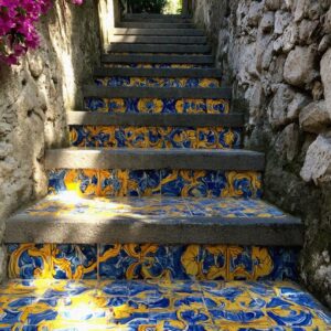 Ceramic tiled staircase with blue and yellow majolica tiles and pink bougainvillea in Ravello Italy