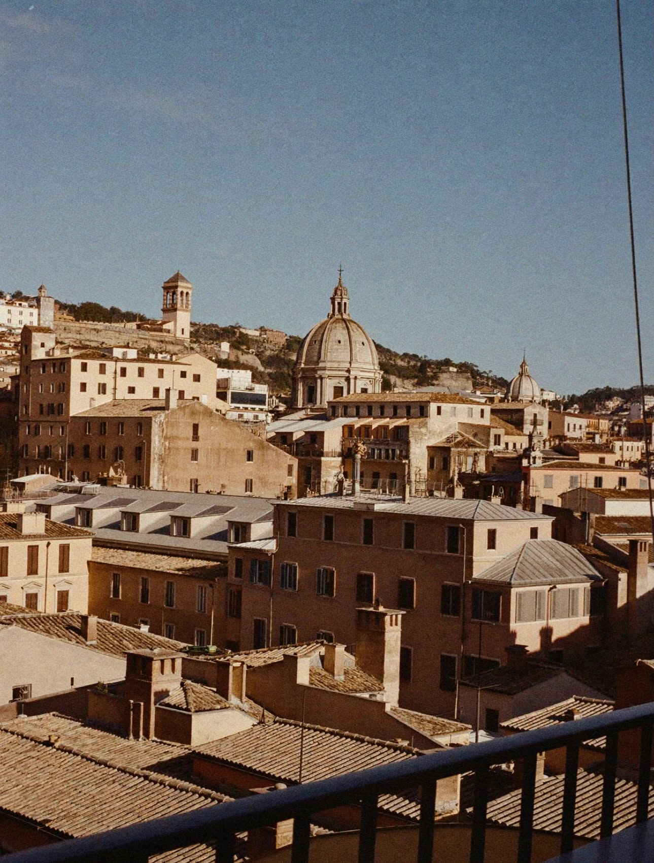 A view over the rooftops and domes of Rome from a terrace at golden hour