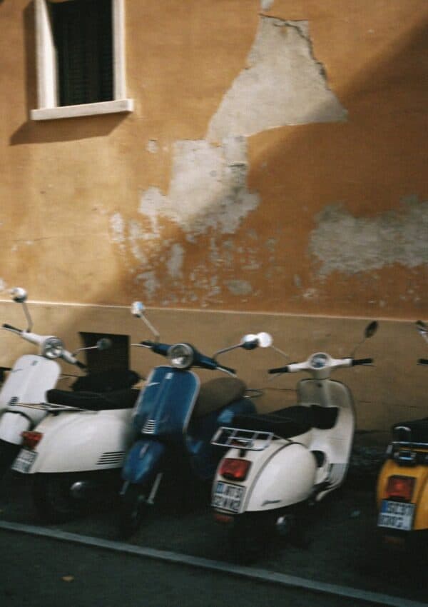 Vintage Vespa scooters parked against a peeling ochre wall in Rome