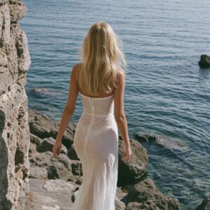Victoria Van Der Berg in a white gown on the rocks by the sea below Amalfi