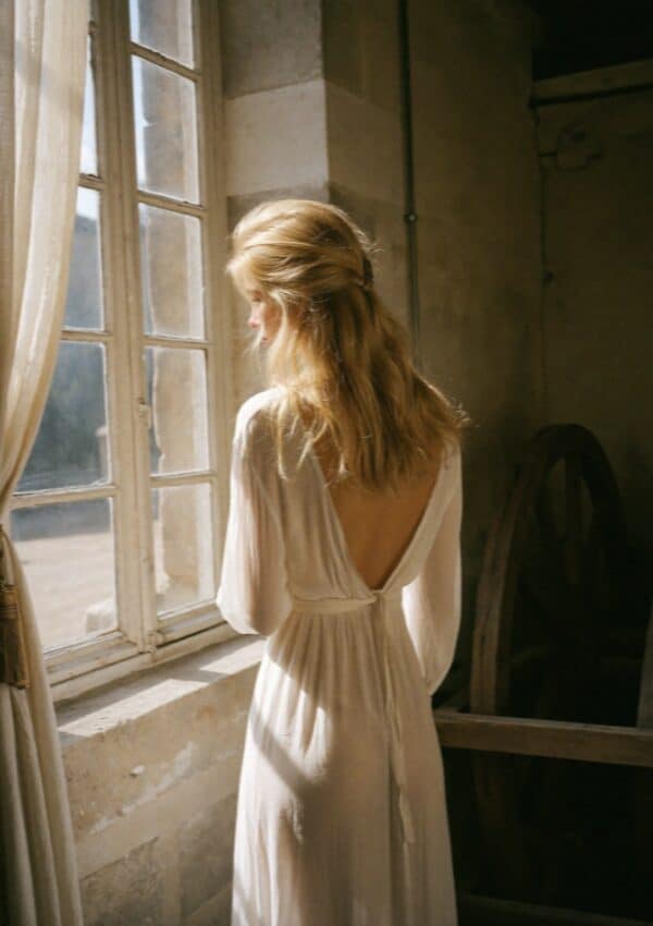 Victoria Van Der Berg by a window in soft light getting ready in Amalfi