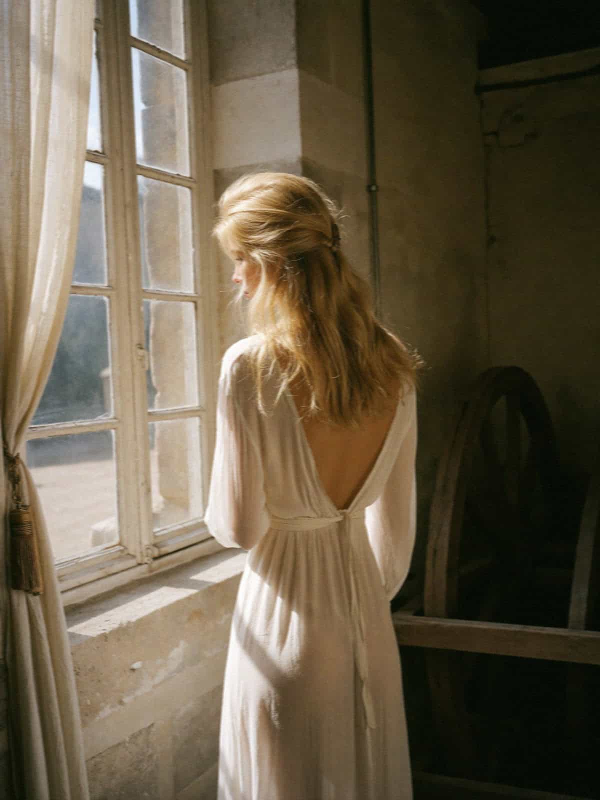 Victoria Van Der Berg by a window in soft light getting ready in Amalfi