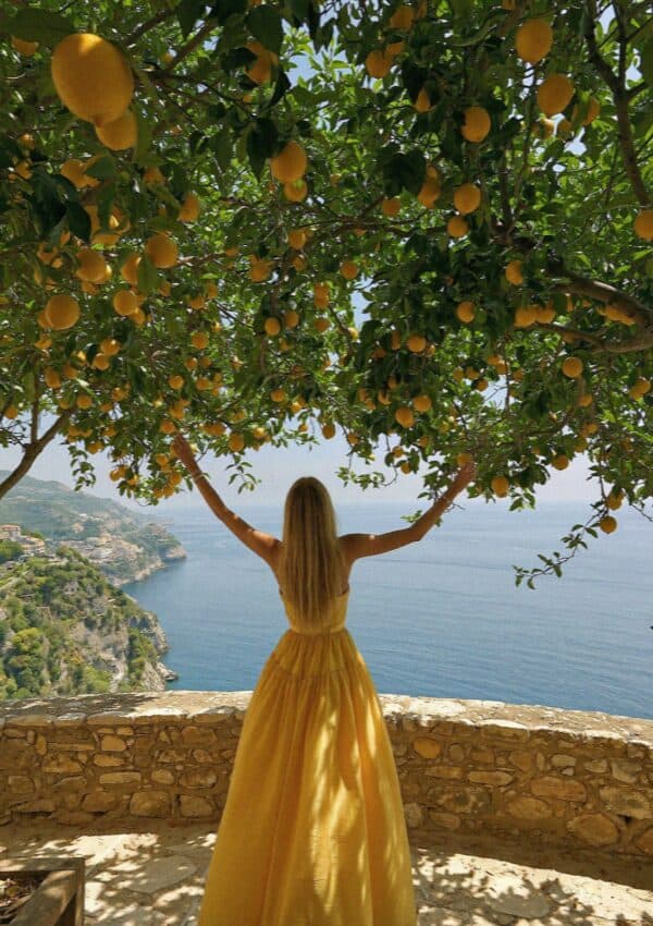 Victoria Van Der Berg in a yellow dress under a lemon tree above the Amalfi Coast