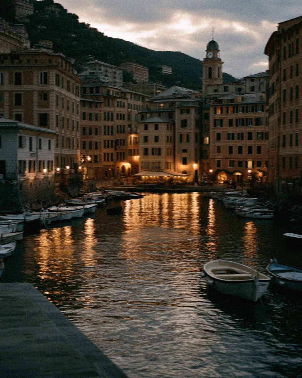 The Camogli harbour at dusk, pastel houses glowing above the calm water