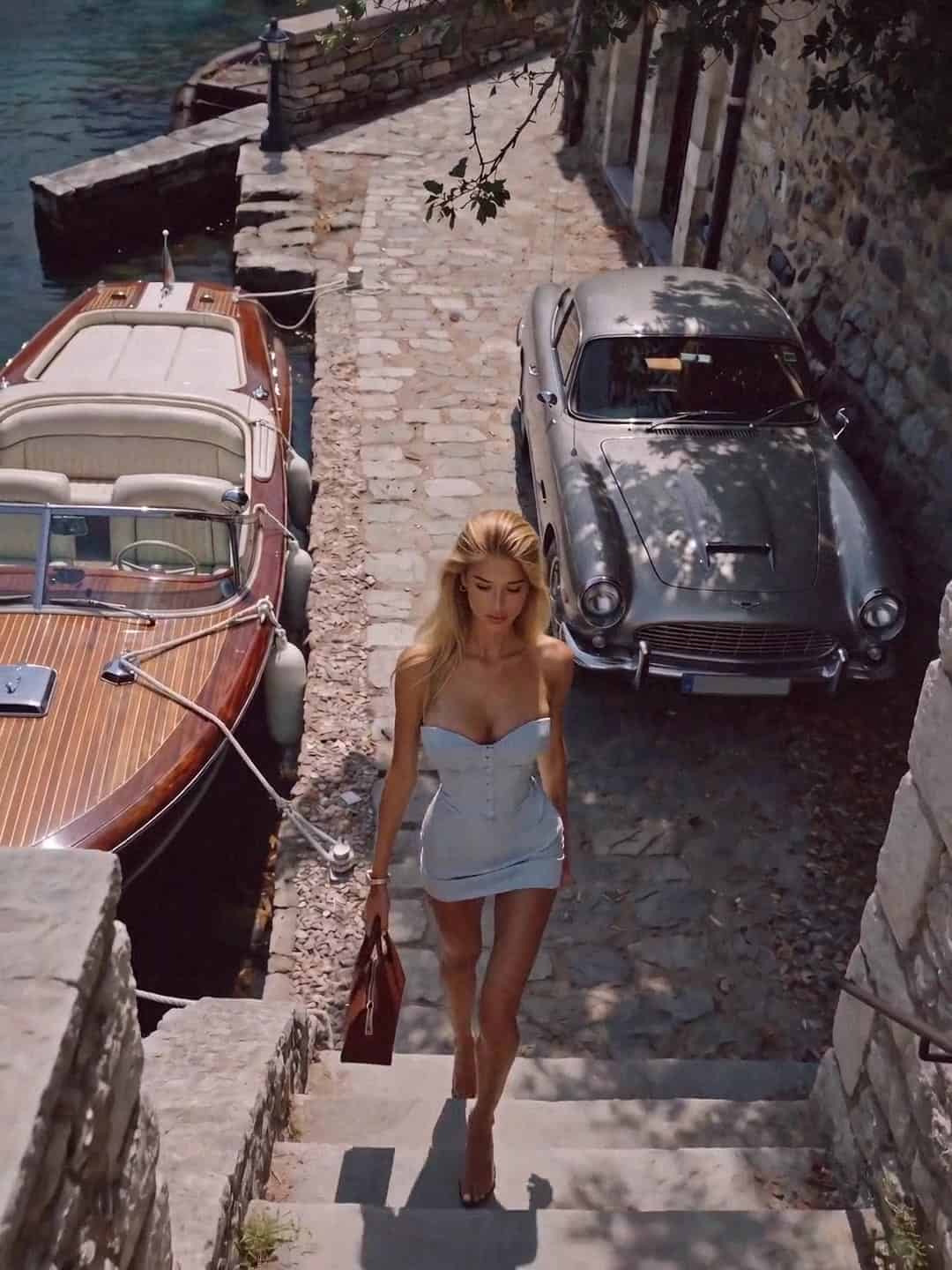 Victoria Van Der Berg beside a Riva and a silver Aston Martin, Lake Como