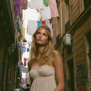 Victoria Van Der Berg looking up in a narrow Quartieri Spagnoli alley in Naples with colourful laundry strung between the balconies overhead