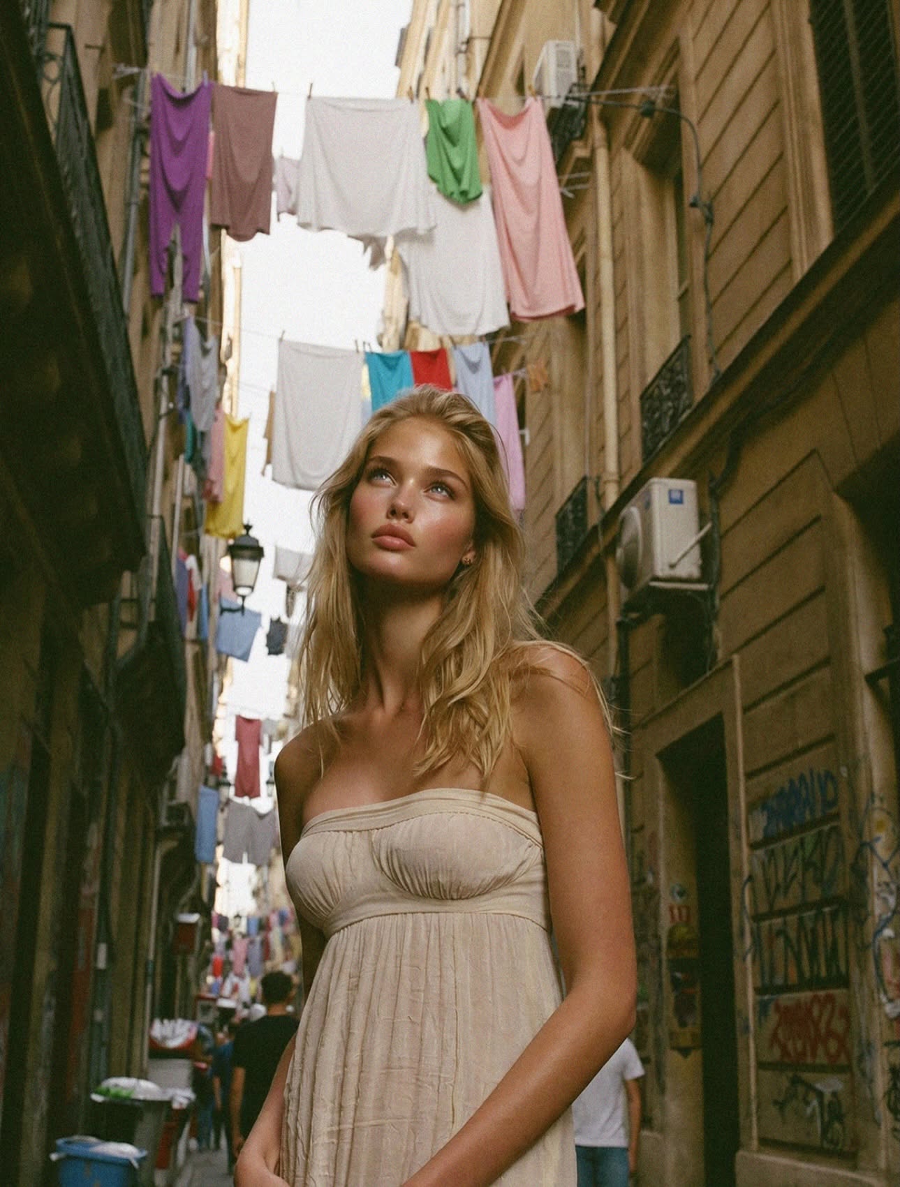 Victoria Van Der Berg looking up in a narrow Quartieri Spagnoli alley in Naples with colourful laundry strung between the balconies overhead