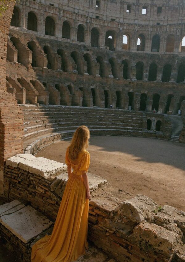 Victoria Vanderberg in a yellow dress looking out over the arena inside the Colosseum in Rome