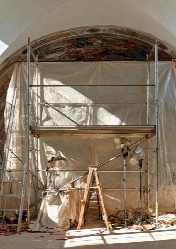 Restoration scaffolding and dust sheets standing against a frescoed vault inside the basilica at Assisi