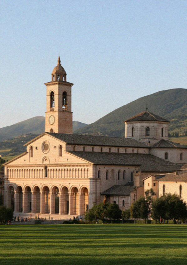 The Basilica of San Francesco in Assisi, its arcaded portico and bell tower in warm afternoon light