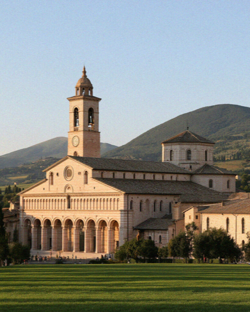 The Basilica of San Francesco in Assisi, its arcaded portico and bell tower in warm afternoon light