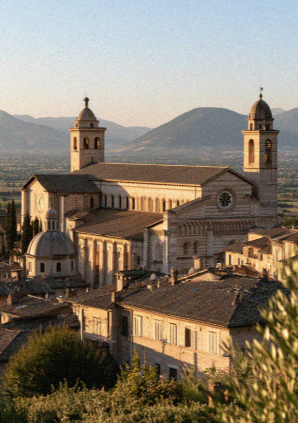 The Basilica of San Francesco and Assisi rooftops at golden hour above the valley