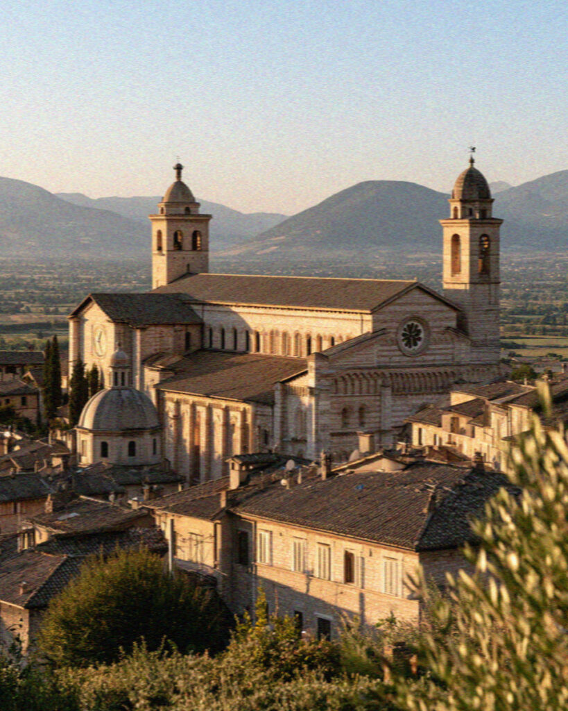 The Basilica of San Francesco and Assisi rooftops at golden hour above the valley